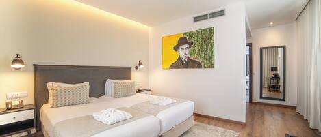 A modern hotel room with a large bed, bedside tables, a painting on the wall, and a view of the hallway.