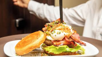 Un sándwich de desayuno con tocino, huevo y lechuga sobre un plato blanco.