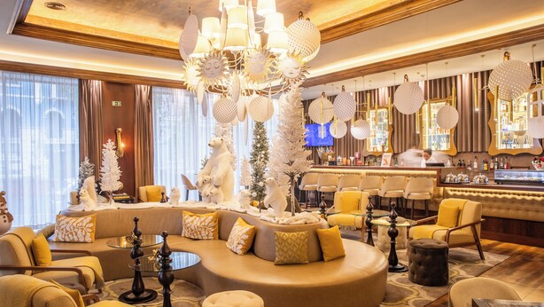 A modern hotel lobby with a curved seating area, a bar, and a Christmas tree.