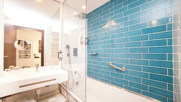 Casa de banho com chuveiro em cabine de vidro, lavatório branco e parede revestida a azulejos azuis.