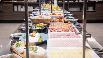 Un bufé con diversos alimentos, incluyendo carnes, quesos y ensaladas.