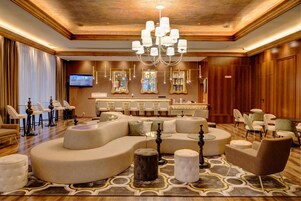 A spacious lobby with a large seating area, a bar, and a television screen.