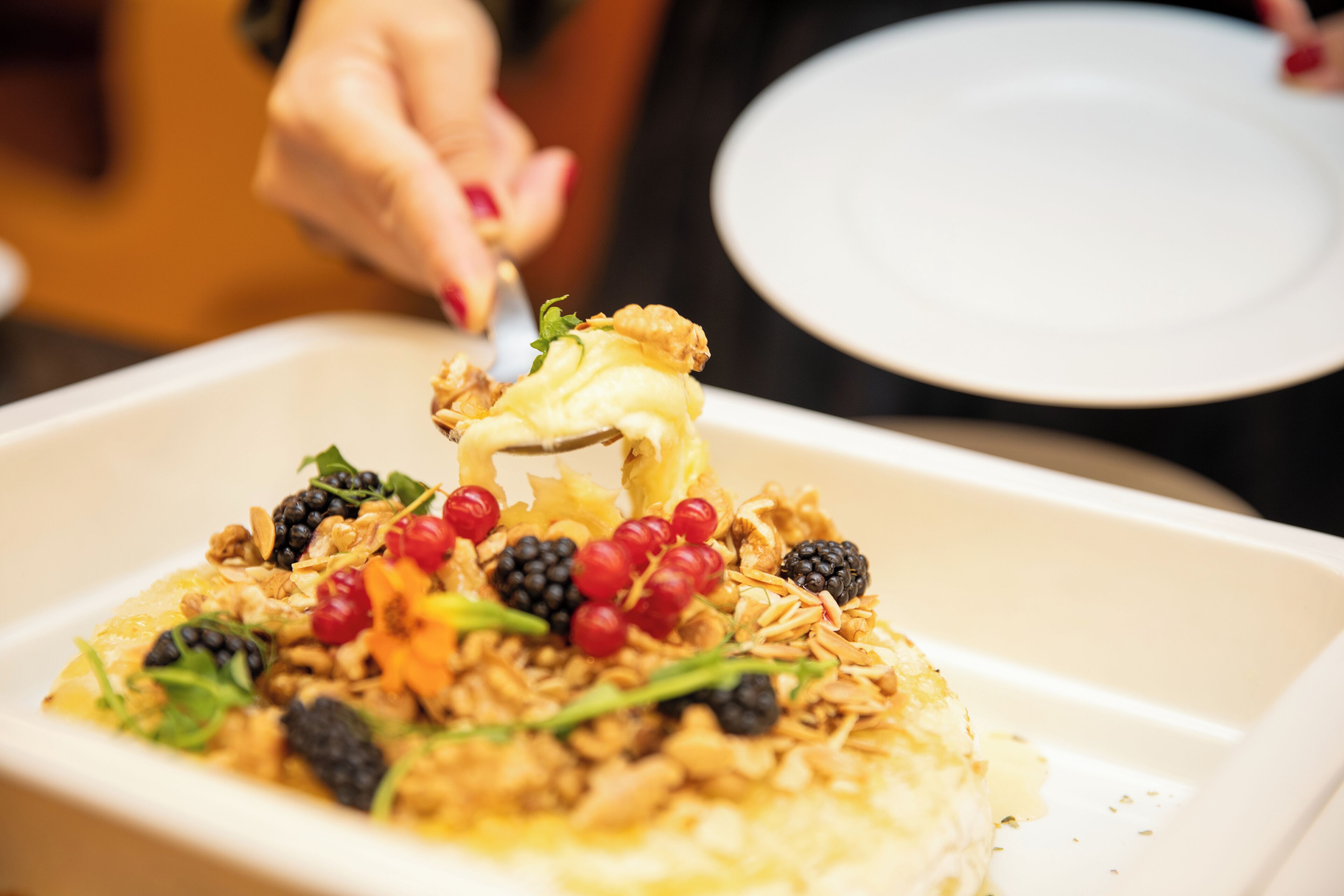 A dessert with berries and nuts on a white plate.