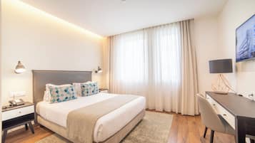 Una habitación de hotel moderna con una cama grande, mesitas de noche, un escritorio y una silla.