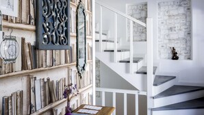 A staircase with white railings and dark steps, leading to a landing with a decorative mirror and framed certificates on the wall. - Bademlik Otel (Bozcaada)