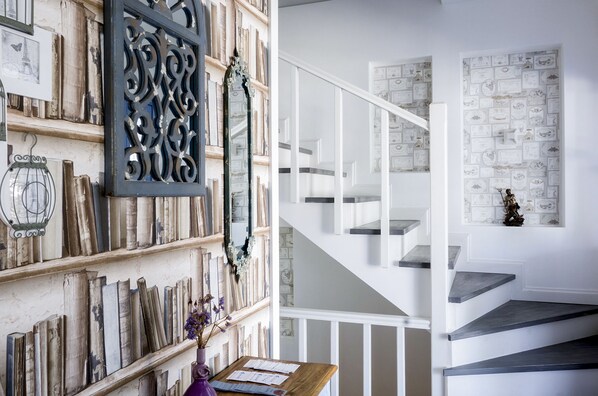 A staircase with white railings and dark steps, leading to a landing with a decorative mirror and framed certificates on the wall.