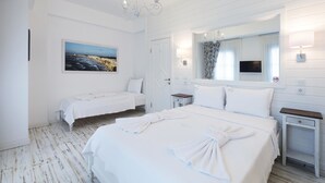 A hotel room with a large bed, a smaller bed, a painting of wind turbines, a mirror, and a television. - Bademlik Otel (Bozcaada)