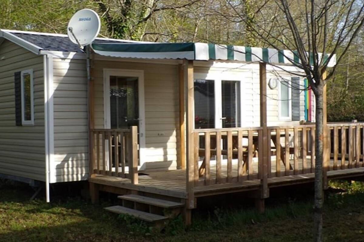 Een klein, gelijkvloers huisje met een veranda en een schotelantenne.