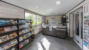 A modern reception area with a counter, a bulletin board, and a display of brochures. - Camping La Cailletiere - Mobil-Home (Dolus-d'Oleron)