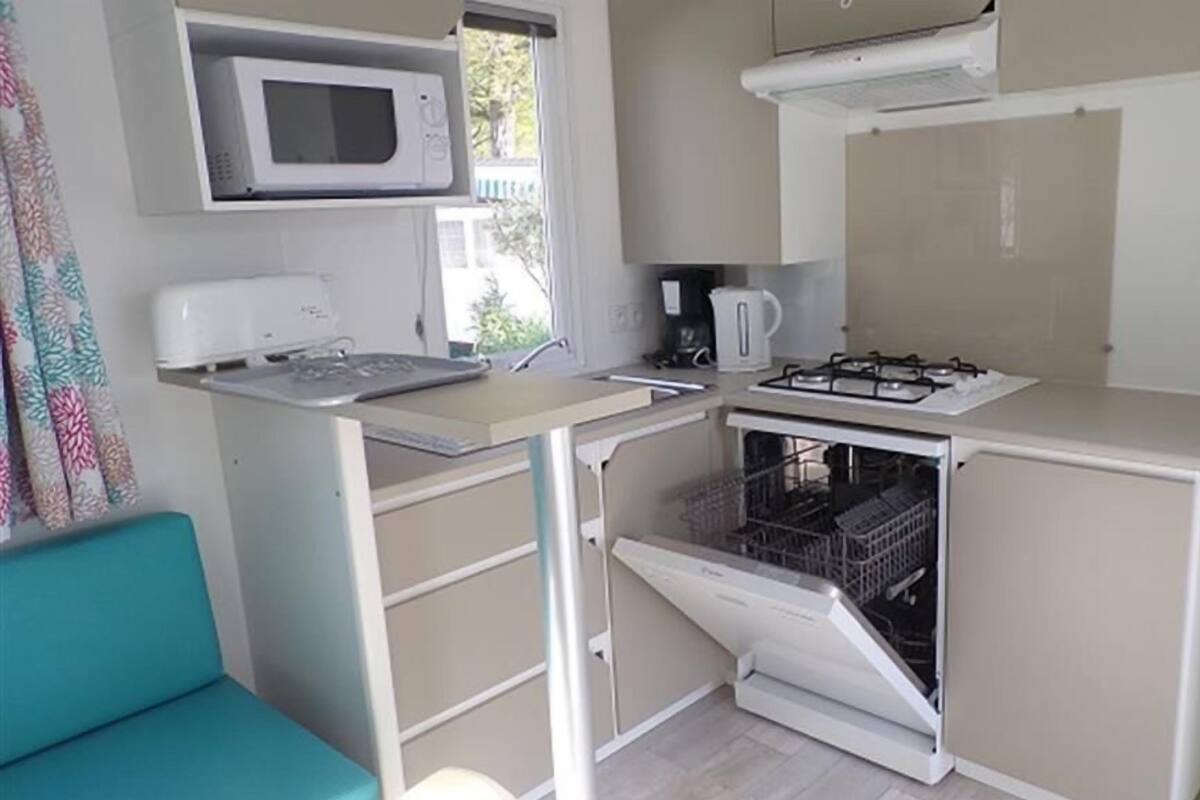 Une petite cuisine équipée d’un four à micro-ondes, d’une cuisinière et d’un lave-vaisselle.