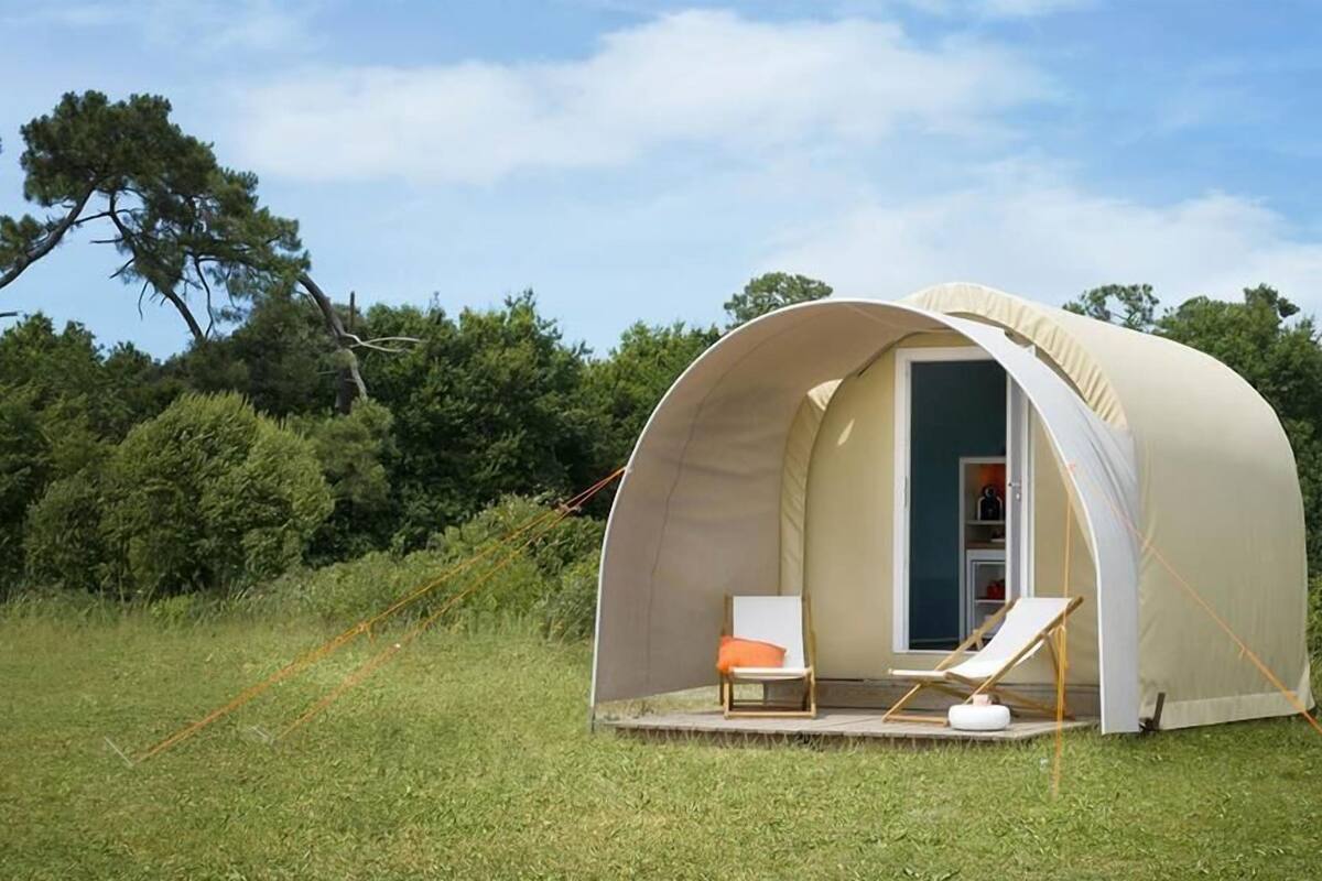Une tente en forme de dôme, dotée d’une porte, d’un petit porche et de deux chaises.