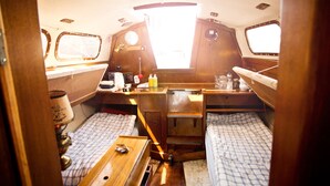 A compact boat interior with a small kitchen area, two sleeping berths, and a window providing natural light. - Klabauterbett (Bremen)