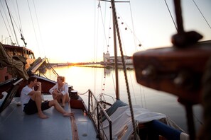 A boat with two people sitting on the deck, a railing, and a view of the water. - Klabauterbett (Bremen)
