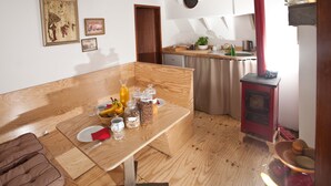 A cozy kitchen with wooden furniture, a red stove, and a dining table set with fruits and jars. - Klabauterbett (Bremen)