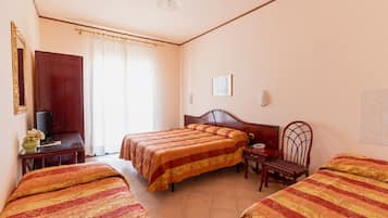 Habitación de hotel con dos camas, un escritorio con silla, televisión y ventana con cortinas.