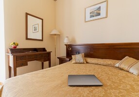 A neatly arranged hotel room with a bed, a desk, and a lamp.