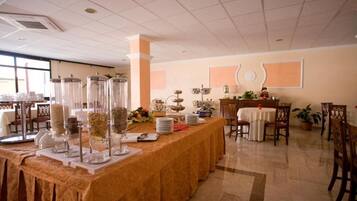 Un buffet con distributori trasparenti per salse e condimenti, una varietà di piatti e un tavolo con tovaglia bianca.