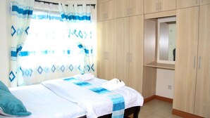 A bedroom with a bed, a wardrobe, and a mirror. - Jambo Homestay (Syokimau)