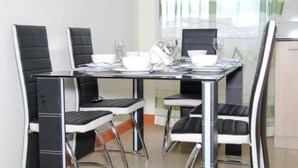 A dining area with a table set for four, surrounded by black and white chairs. - Jambo Homestay (Syokimau)