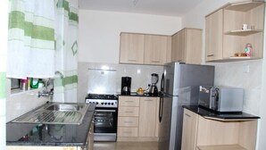 A compact kitchen with a sink, stove, oven, refrigerator, and a small countertop with a toaster. - Jambo Homestay (Syokimau)