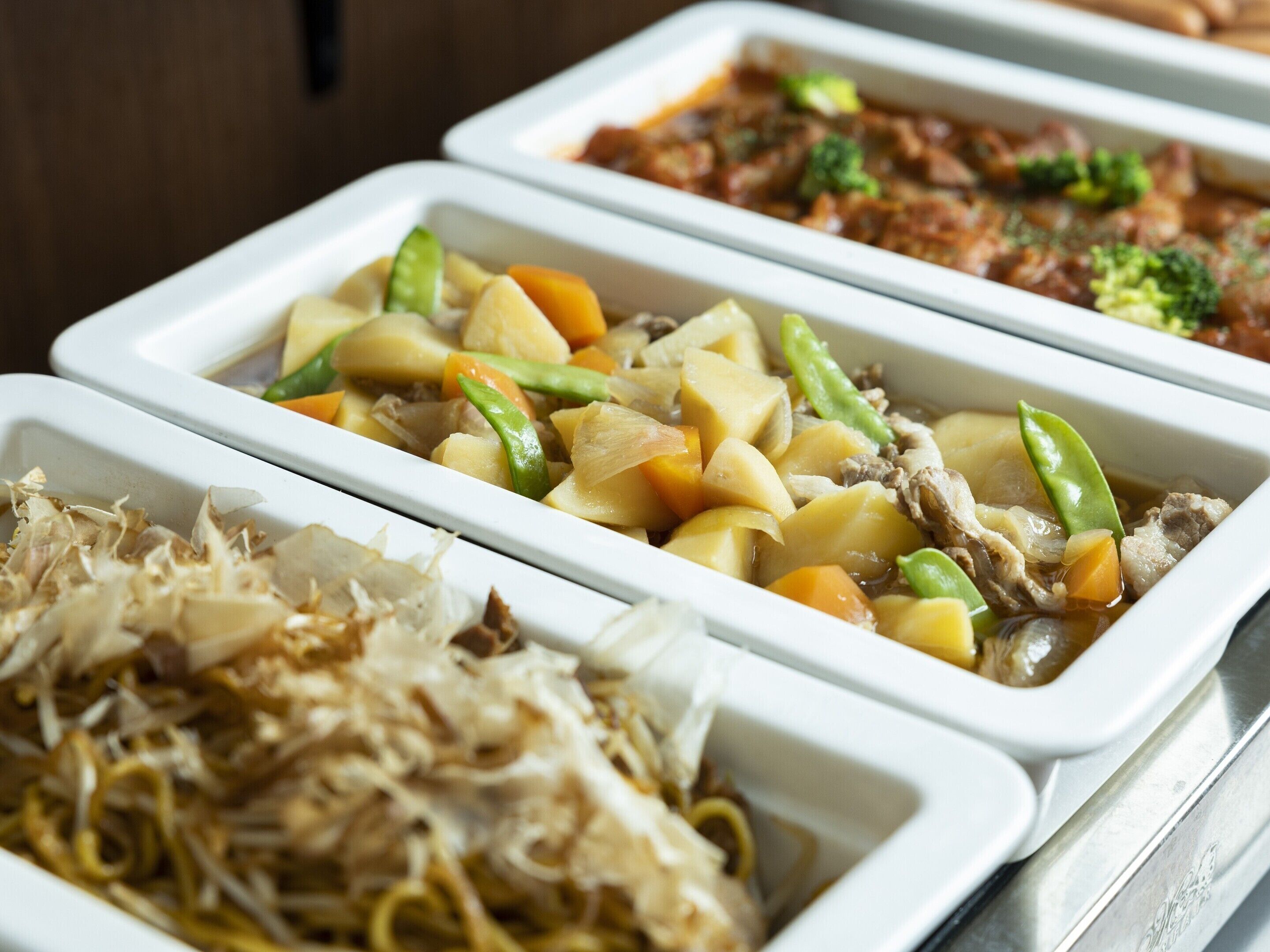 A buffet with various dishes including noodles, vegetables, and meat.