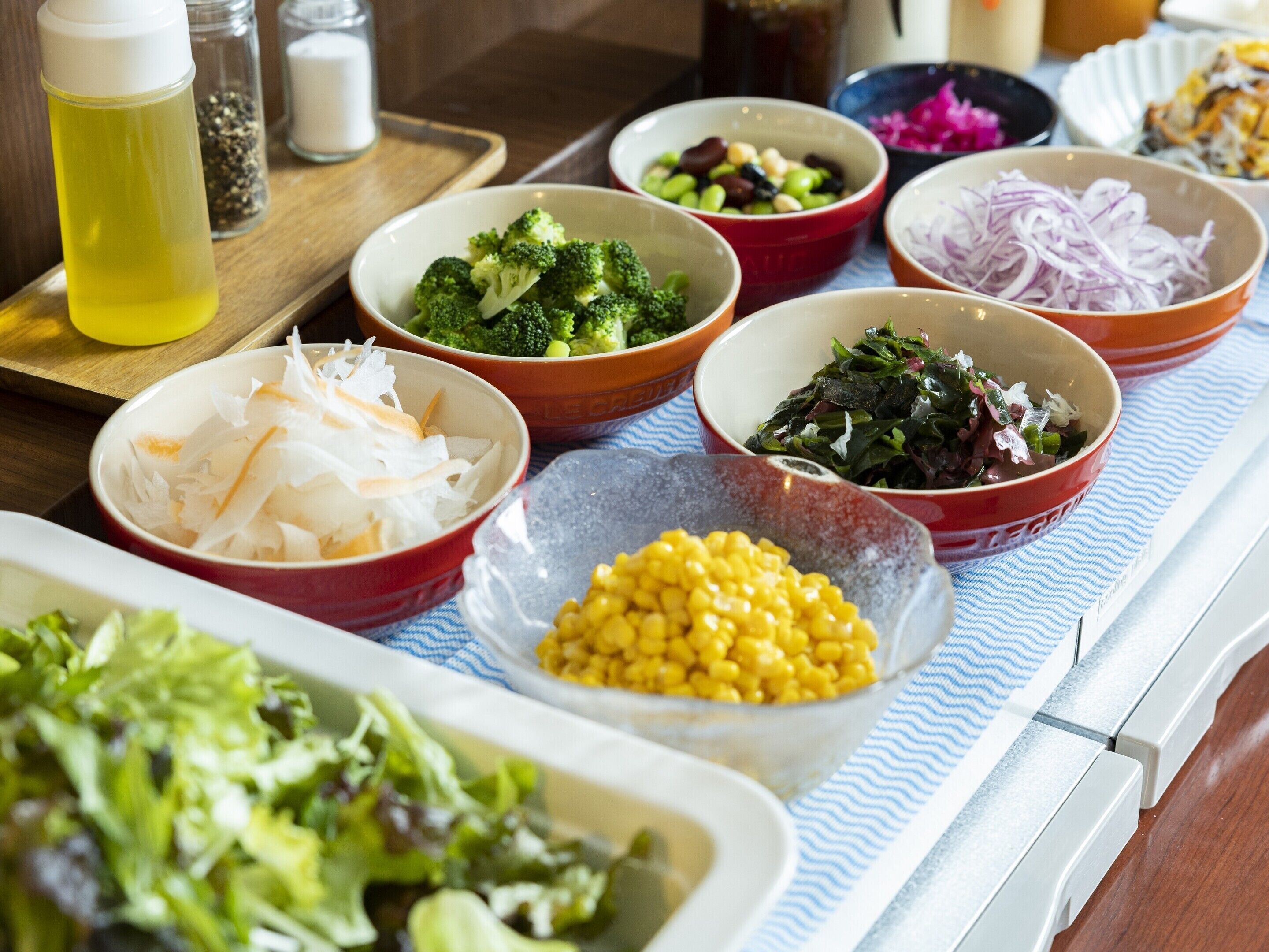 A variety of food bowls on a table with a blue and white striped cloth.
