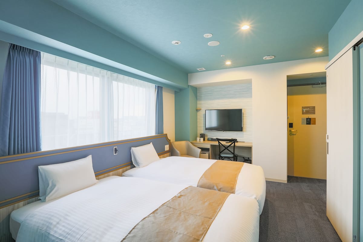 Hotellihuone, jossa on kaksi sänkyä, työpöytä, televisio ja kylpyhuoneen ovi.