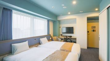 A hotel room with two beds, a desk, a television, and a bathroom door.