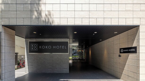 Ein moderner Hotelzugang mit einem Schild, auf dem 'KOKO HOTEL' steht.
