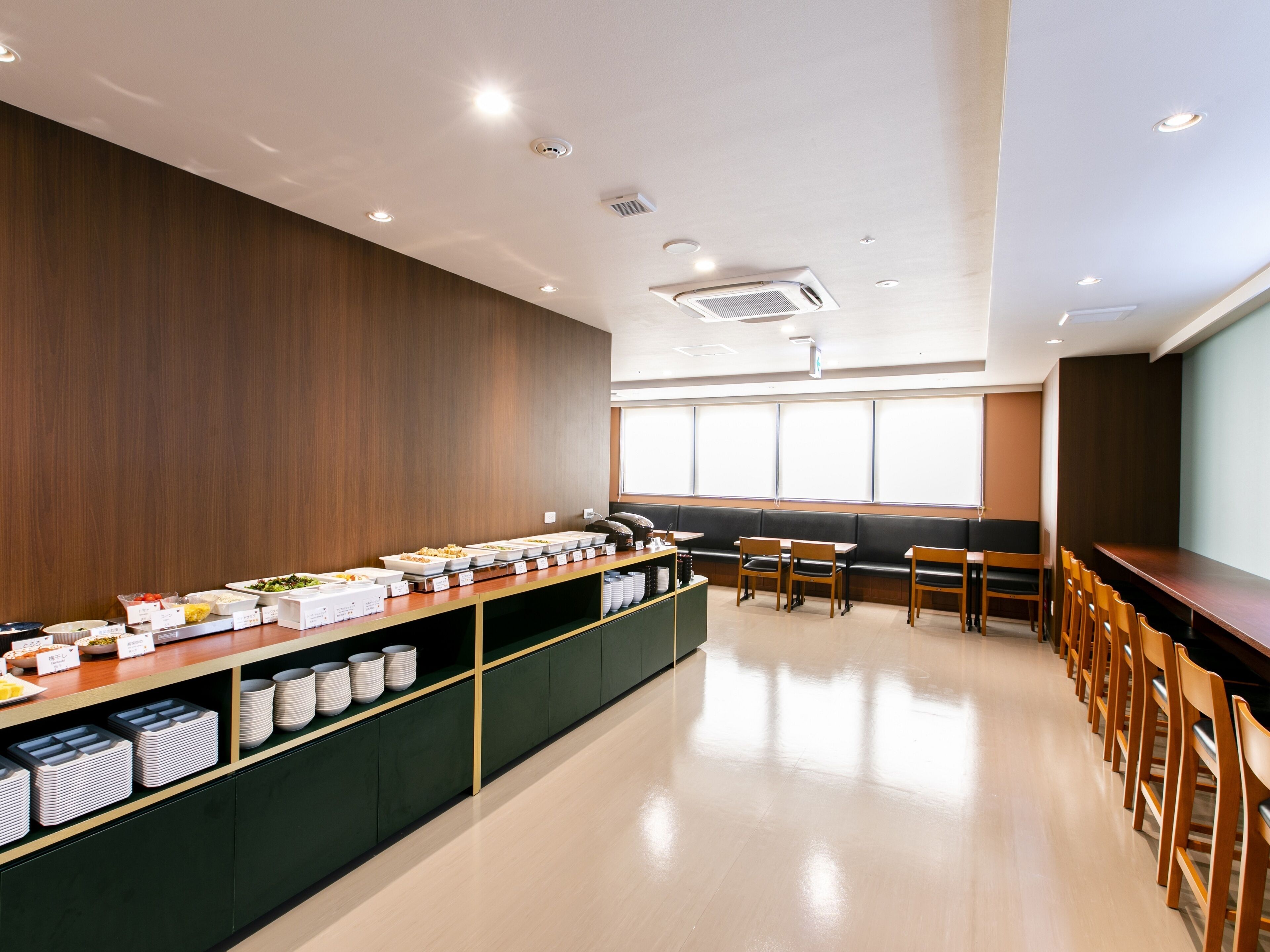 A spacious room with a buffet setup, seating area, and a large window providing natural light.