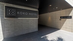 Ein moderner Hotel Eingang mit einem Schild, auf dem 'KOKO HOTEL' steht, und einem Fliesenboden.