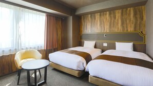 Ein Hotelzimmer mit zwei Betten, einem kleinen runden Tisch und einem Stuhl.