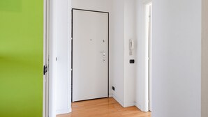 Une pièce avec une porte blanche fermée, un chambranle de porte vert et un mur blanc sur lequel est fixé un téléphone.