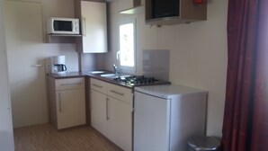A compact kitchen with a microwave, stove, sink, and a small refrigerator.