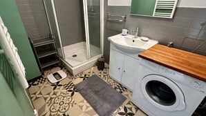 A bathroom with a shower, sink, and washing machine.