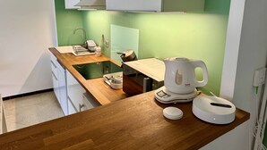 A kitchen with a wooden countertop, a kettle, a scale, and a coffee maker.