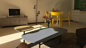 A living room with a TV, a lamp, a dining table with chairs, and a sofa.