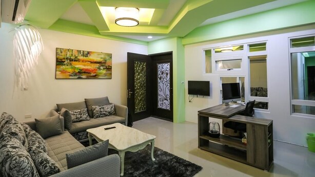 A living room with a sofa set, a coffee table, and a TV. - Return Home B&B (Yuli)