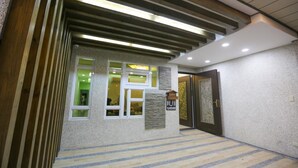A modern hotel lobby with a wooden staircase, a reception desk, and a patterned floor. - Return Home B&B (Yuli)