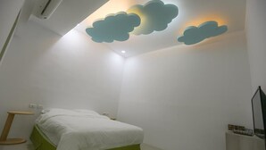 A bedroom with a bed, a nightstand, a wall-mounted shelf, and a ceiling with cloud-shaped lighting. - Return Home B&B (Yuli)
