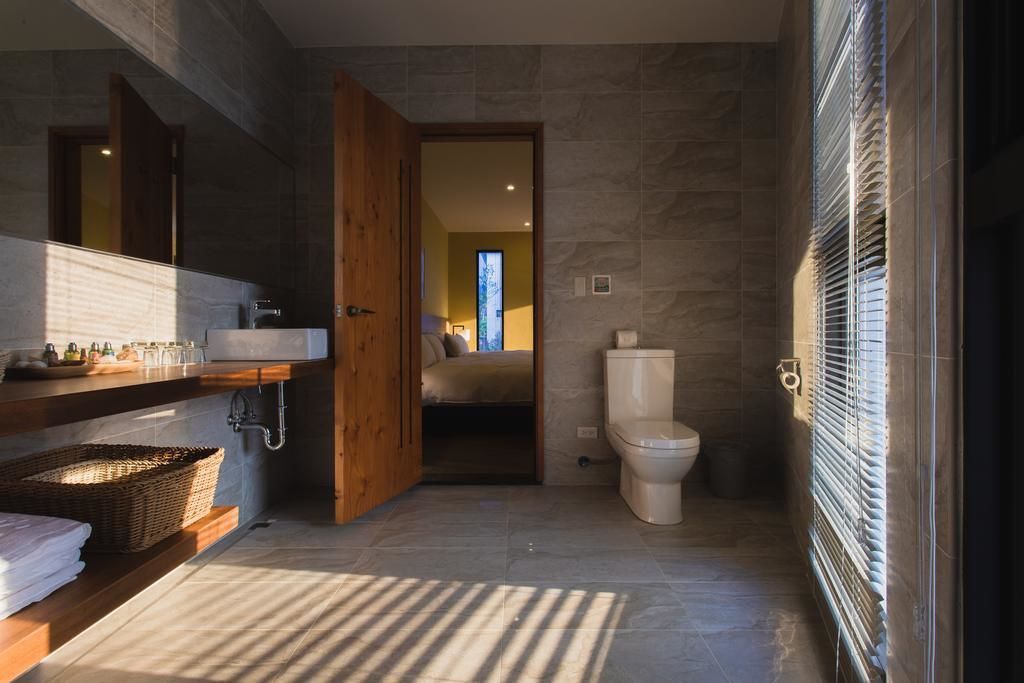 A modern bathroom with a wooden vanity, a toilet, and a shower area.