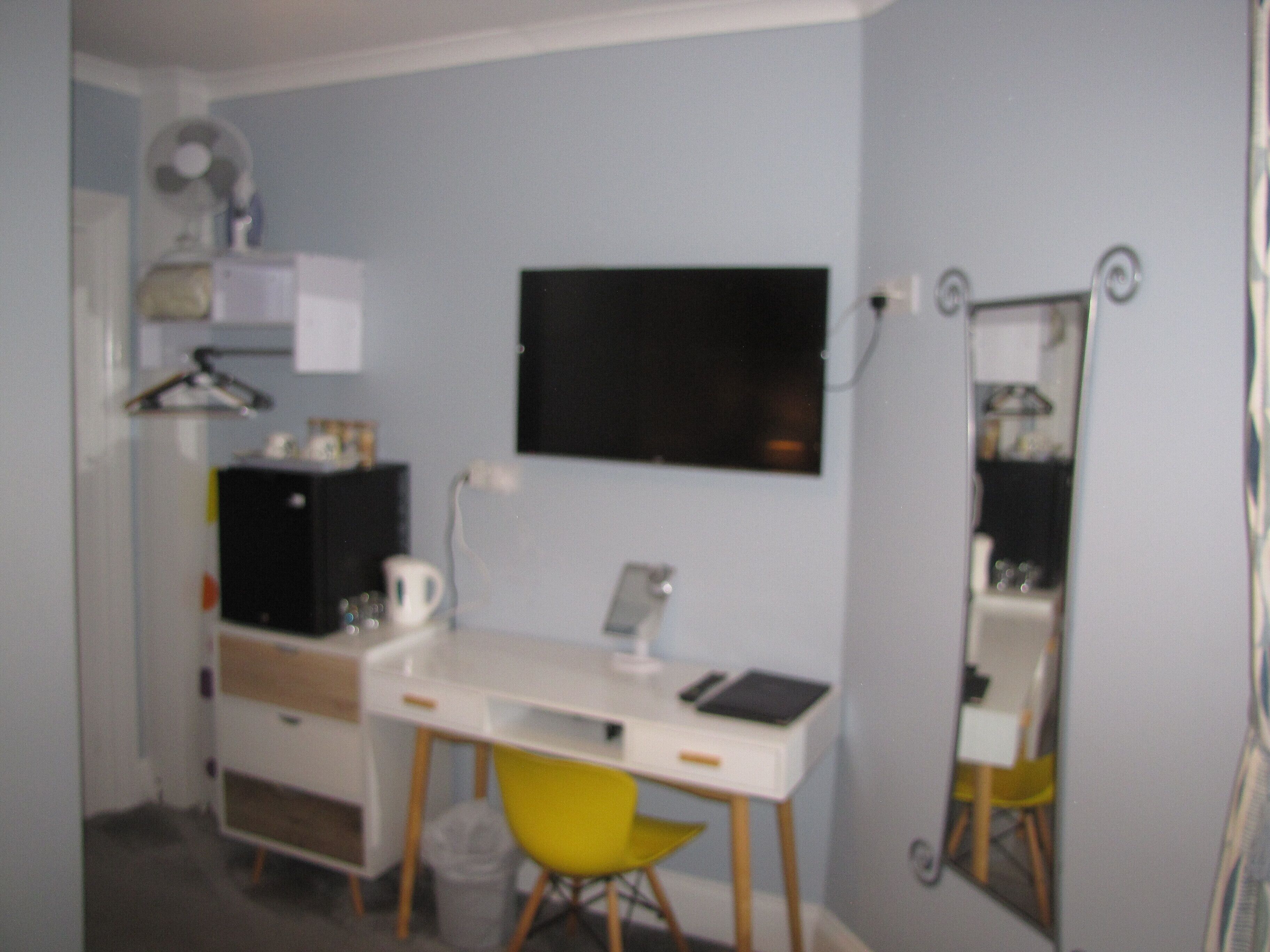 A small, compact room with a desk, chair, and a mirror.