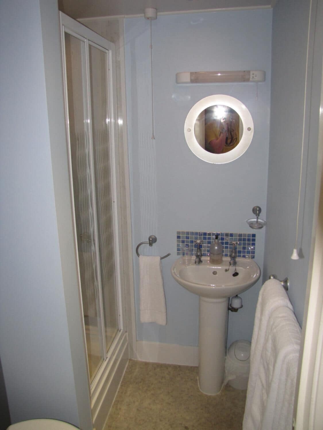 Un baño con ducha, lavamanos y espejo.