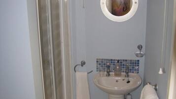 Un baño con ducha, lavamanos y espejo.
