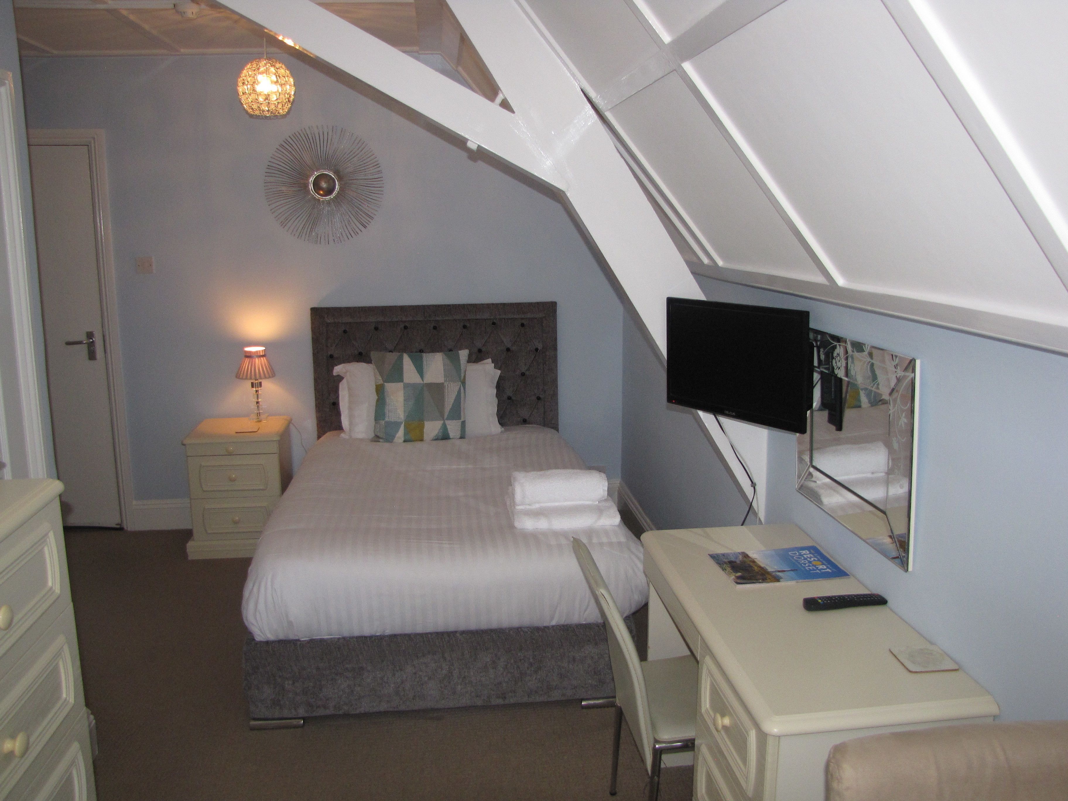 Une chambre à coucher comprenant un lit, une table de chevet, une lampe et un bureau avec un miroir.