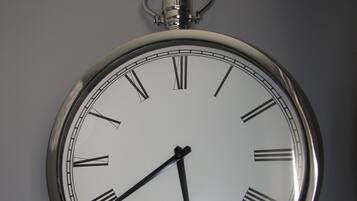 Un reloj de pared analógico con acabado metálico y números romanos.
