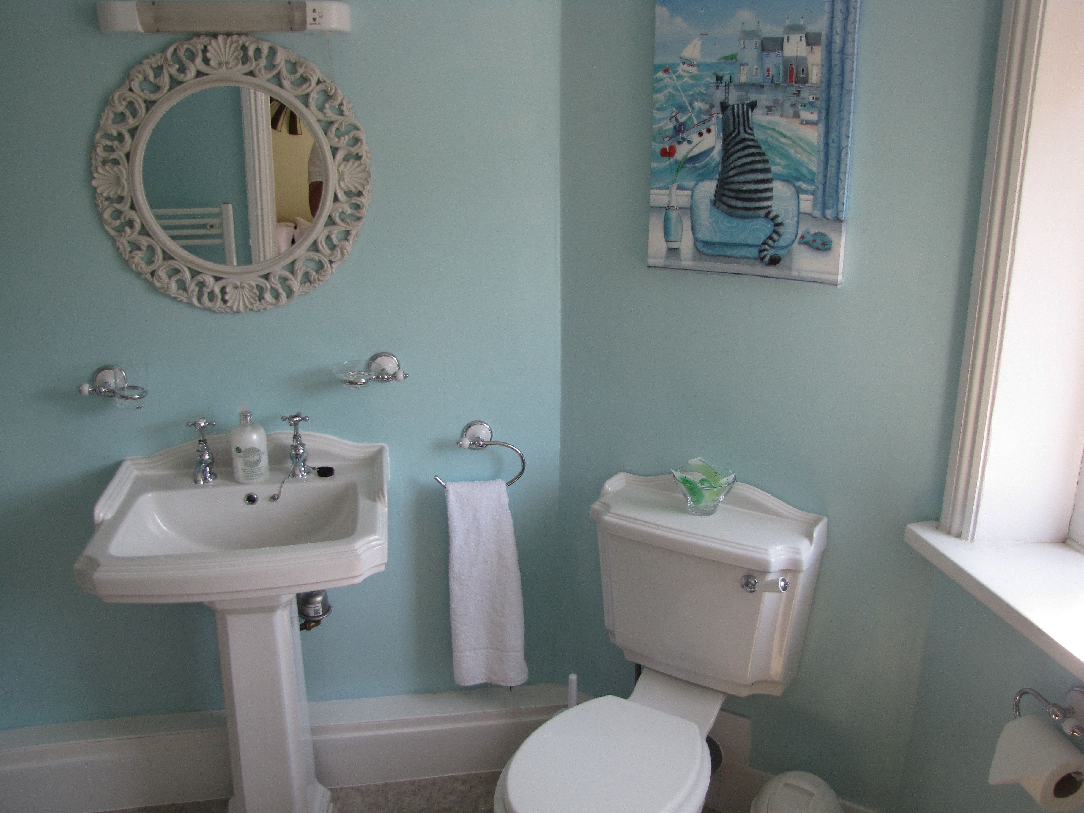 A bathroom with a sink, toilet, and a painting on the wall.