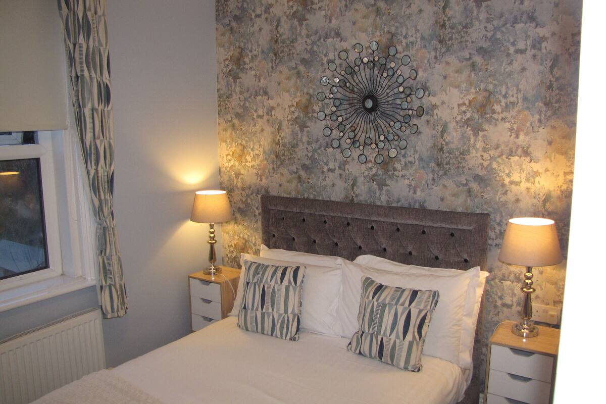 A neatly made bed with two pillows, a decorative wall piece, and two bedside lamps.