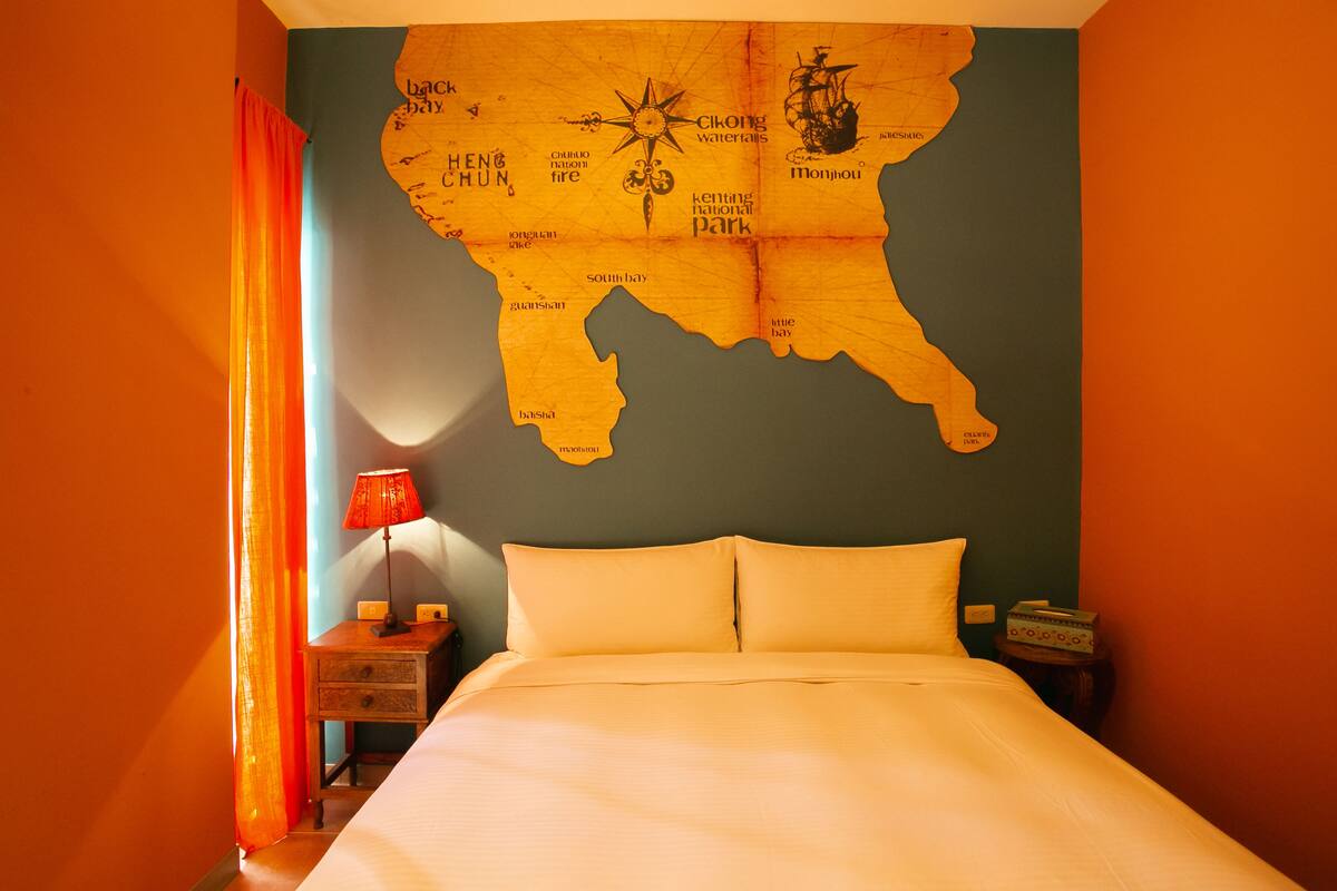 Una habitación de hotel con una cama, una mesita de noche, una lámpara y un mapa mural.