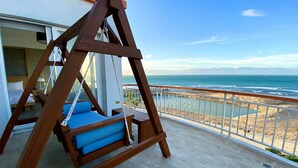 A wooden swing chair with blue cushions on a balcony overlooking a beach. - Blue Sea Sunny Sea View Homestay (Checheng)